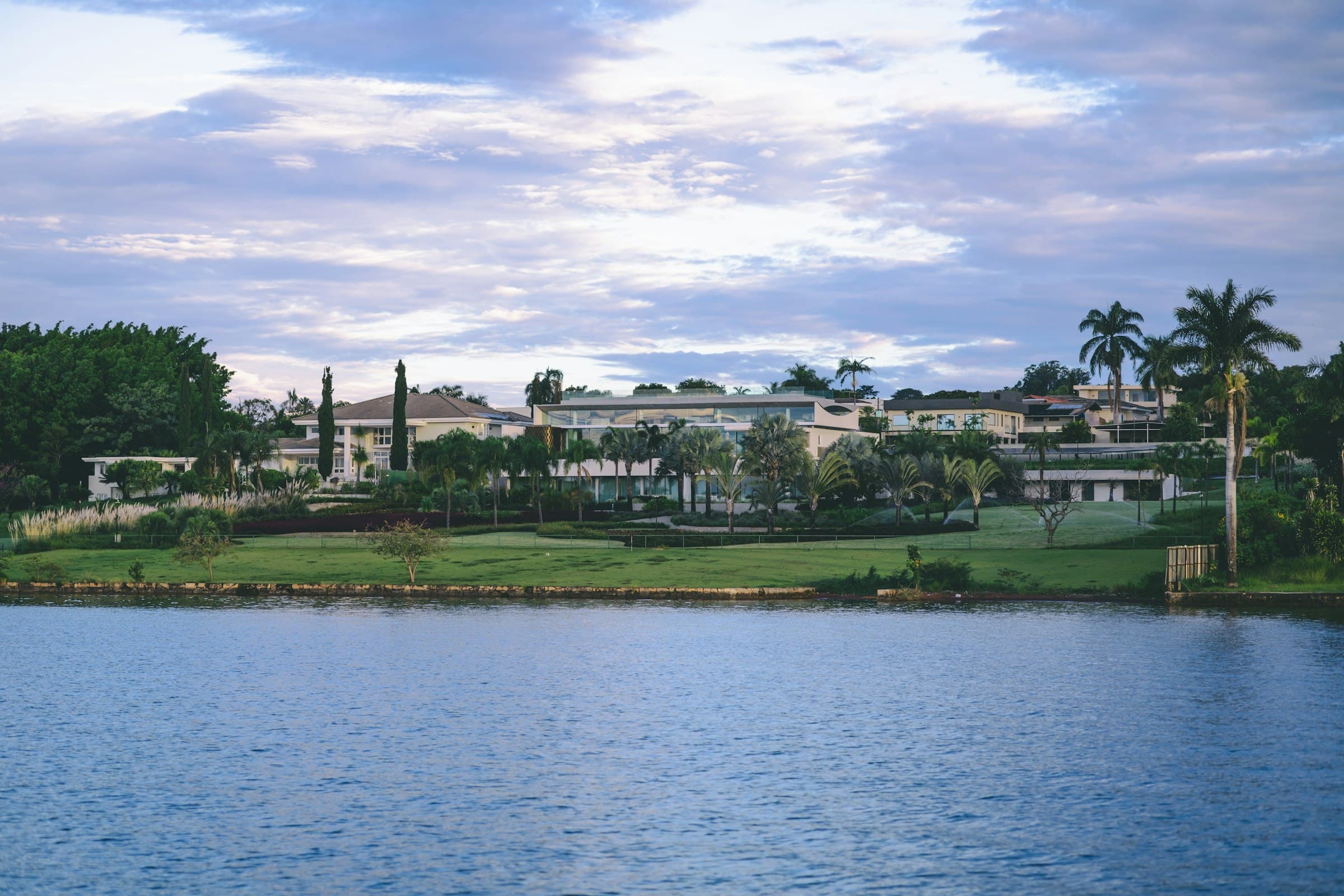 Waterfront estate with manicured lawns, palms and mature planting at dusk